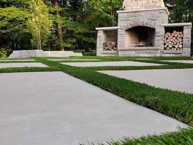 Outdoor fireplace with concrete pavers and artificial turf