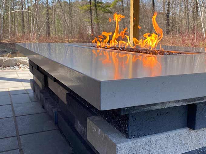 Modern outdoor fire feature on an interlock patio.