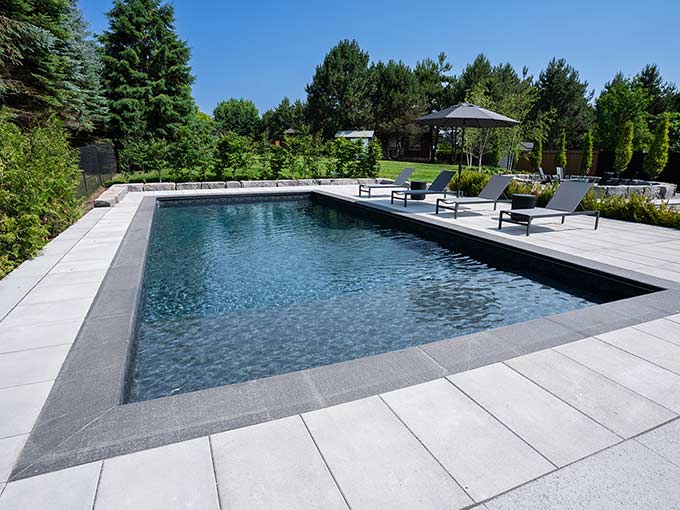 Luxury pool and patio with lounge chairs by Greenblock Landscape