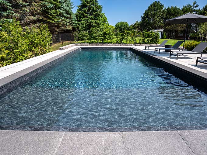 Luxurious backyard with swimming pool and patio by Greenblock Landscape.