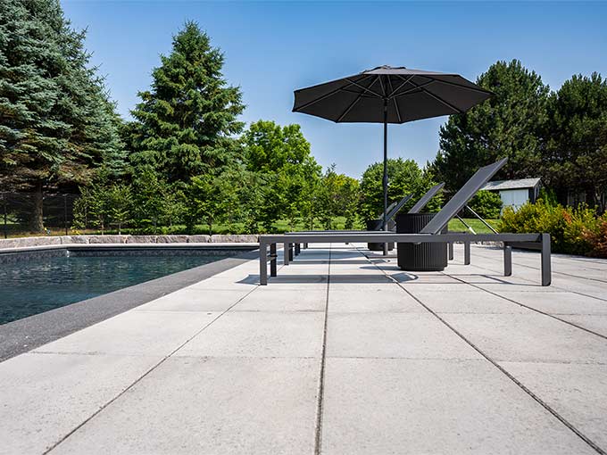 Elegant poolside patio with interlocking pavers and lounge chairs