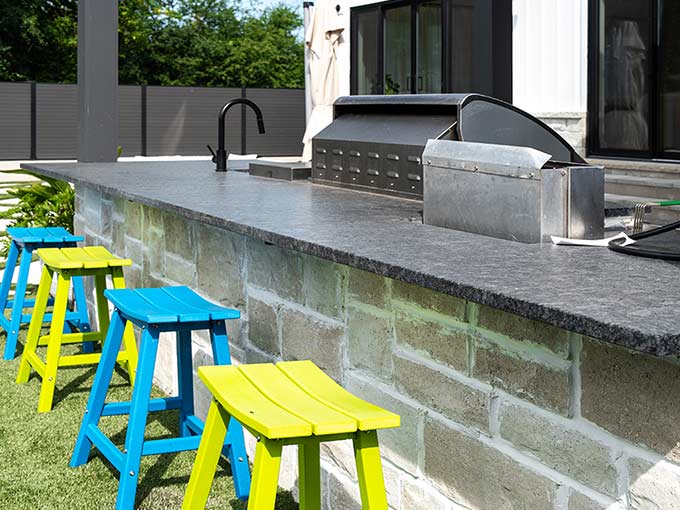 Outdoor kitchen with stonework and bright stools
