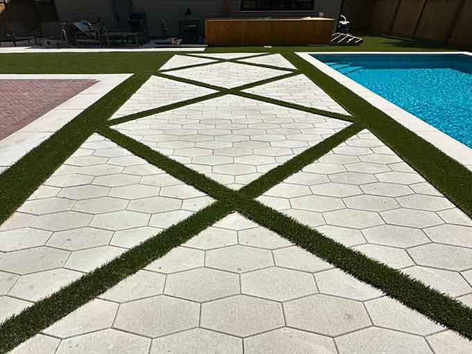 Hexagonal paver patio with turf lines and a swimming pool.