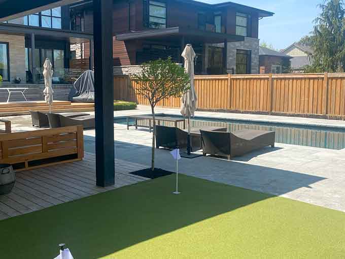 Outdoor patio area with loungers, putting green, and pool.