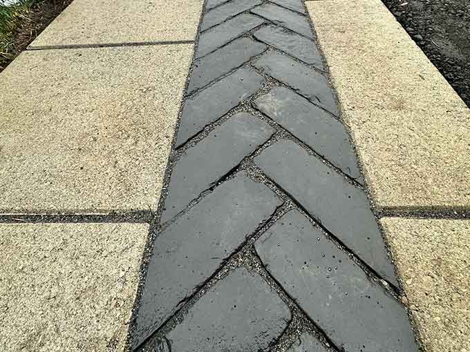 A walkway with herringbone pavers and concrete slabs.