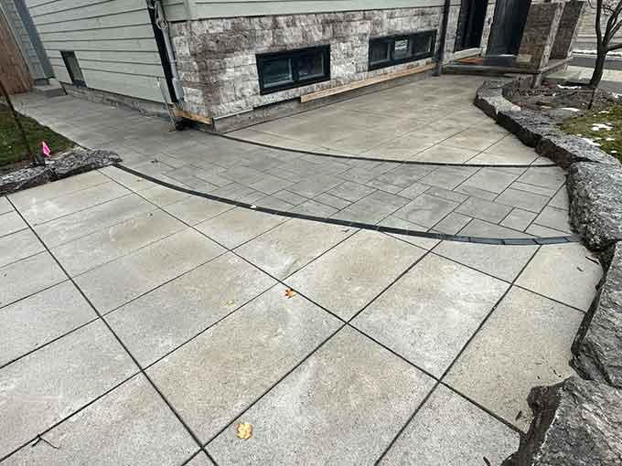 Curved paver patio with a natural stone border at a home entrance.