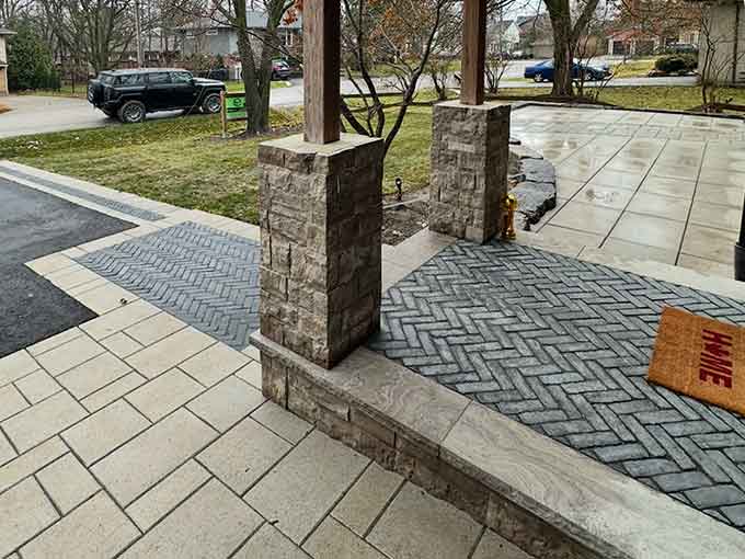 Entrance with herringbone paver walkway and stone columns.