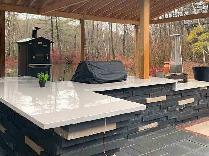 Outdoor kitchen with stone base, countertop, and a black oven.